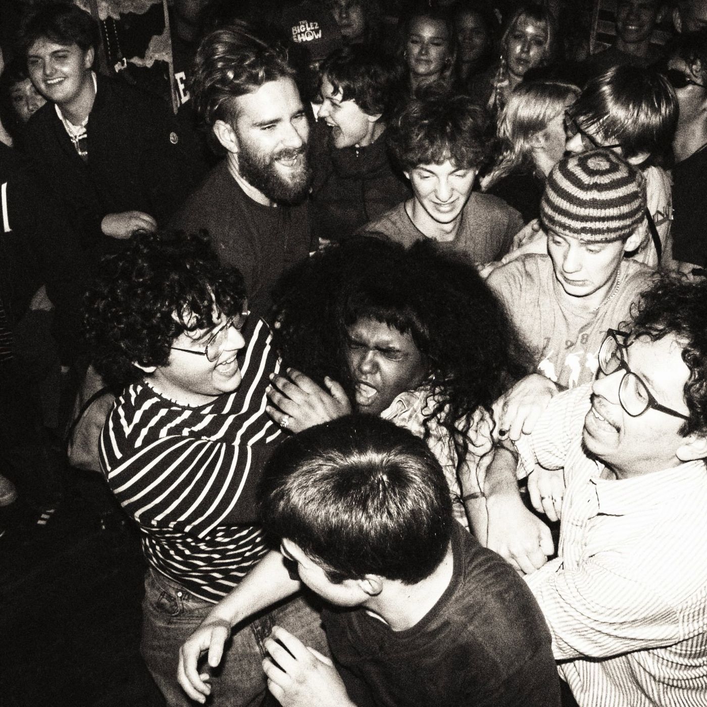 Black-and-white photo of a packed, grinning crowd at the front of the stage