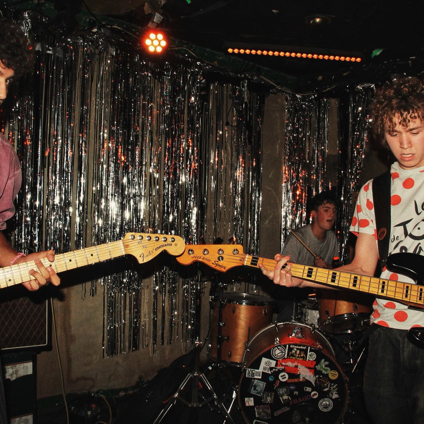 A guitarist in a polka-dot shirt playing beside the drummer