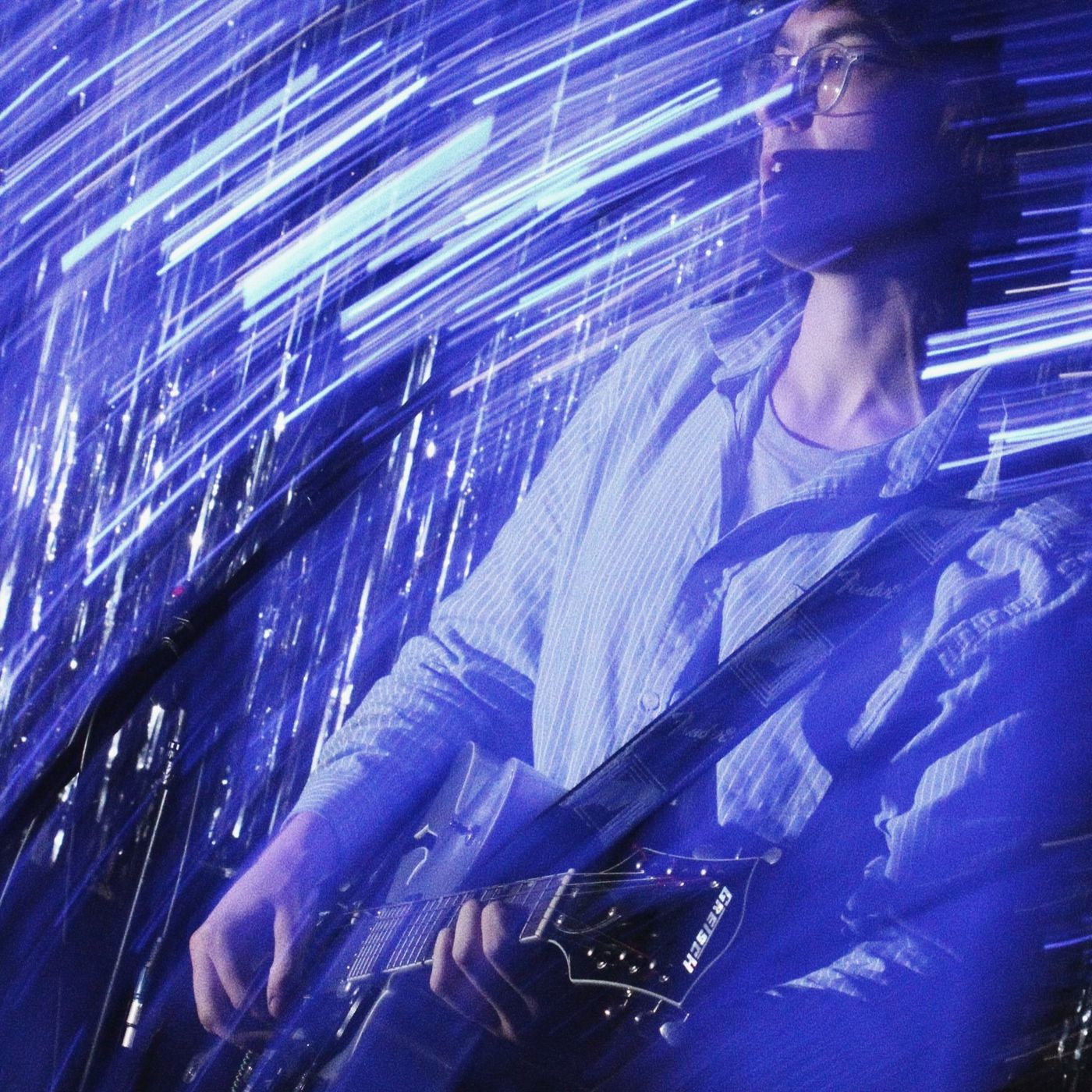 A guitarist lit blue in a long-exposure blur