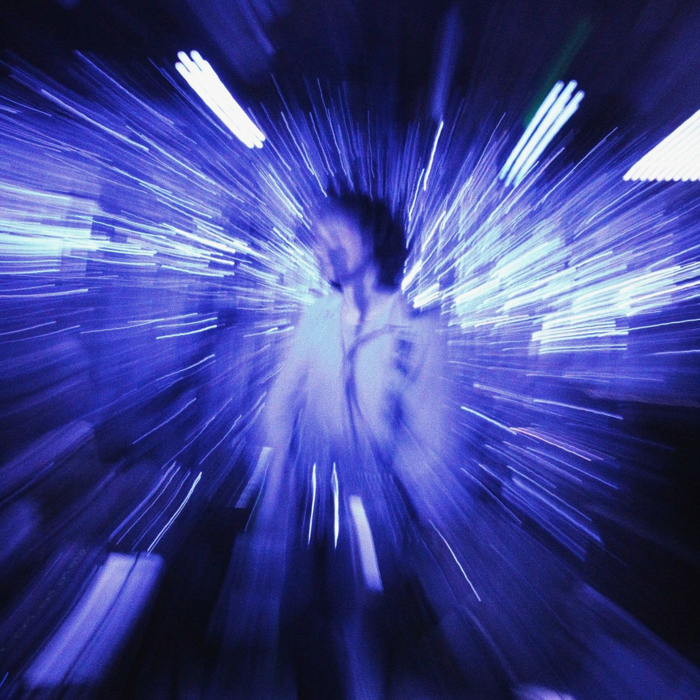 A figure on stage in a blue burst of light