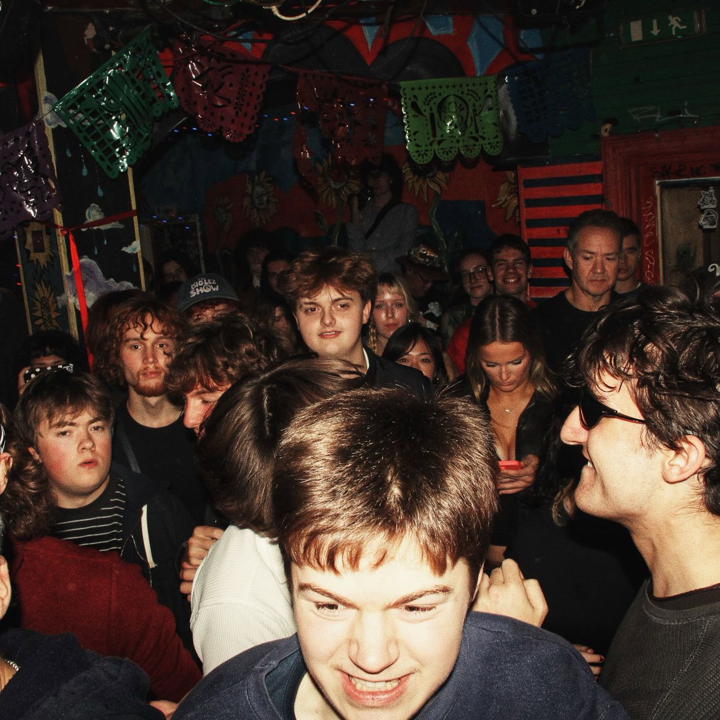 A full room under the bunting, fans smiling at the camera